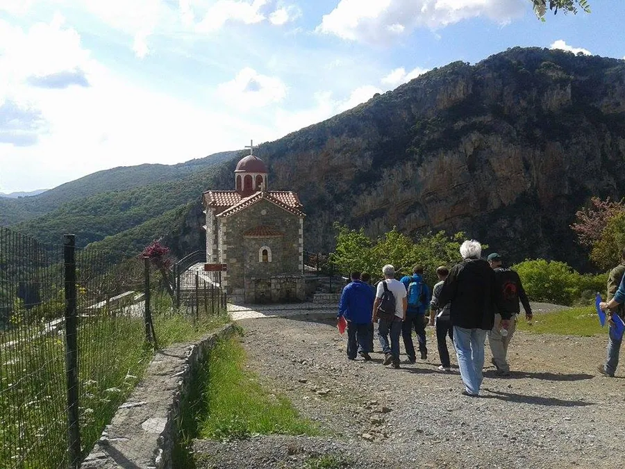Πεζοπόροι στο μονοπάτι με ξωκλήσι και βουνό πίσω